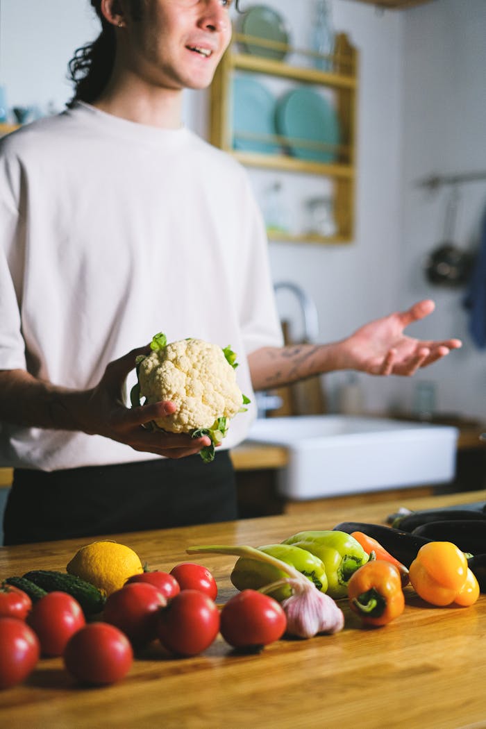 Mastering the First Impression: Your intriguing post title goes here A man holds a cauliflower while preparing fresh vegetables in a modern kitchen.