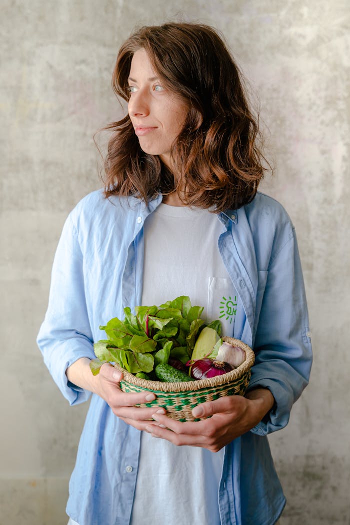 Crafting Captivating Headlines: Your awesome post title goes here Caucasian woman in casual attire holding a basket of fresh vegetables indoors.