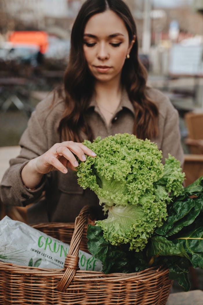 A woman explores fresh green vegetables in a wicker basket outdoors, promoting a healthy lifestyle.